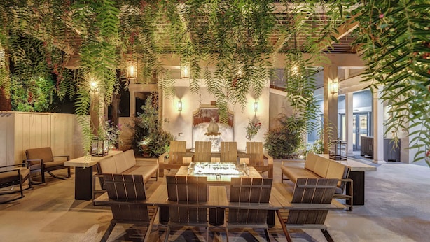 An indoor dining area with a central table surrounded by chairs, a fountain, and hanging plants. - Sonoma Valley Inn, Tapestry Collection by Hilton (Sonoma)