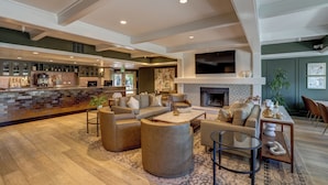 A spacious living area with a bar, sofas, a fireplace, and a TV. - Sonoma Valley Inn, Tapestry Collection by Hilton (Sonoma)