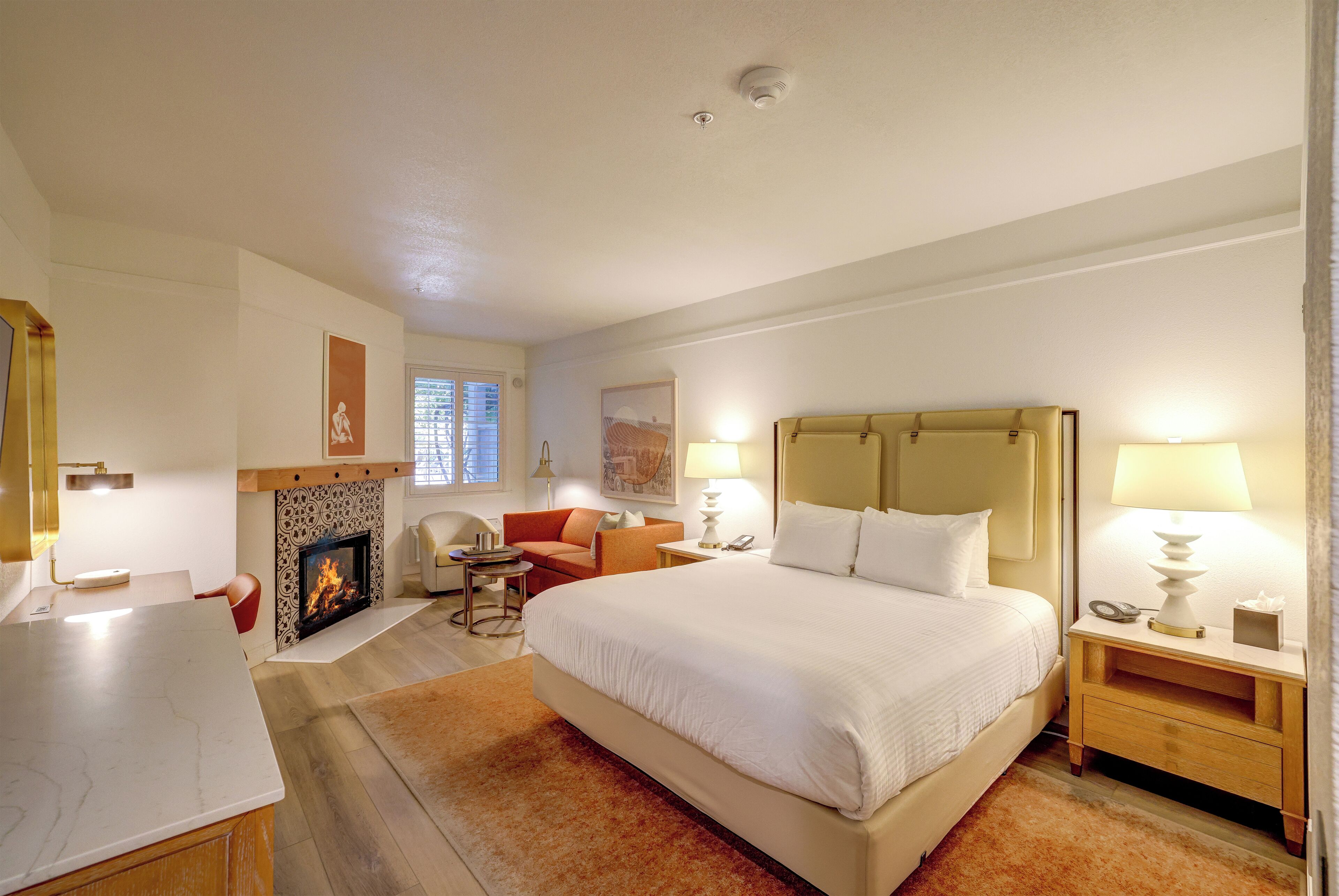 Ein Hotelzimmer mit einem großen Bett, einem Kamin, einem Schreibtisch und einem Sessel.