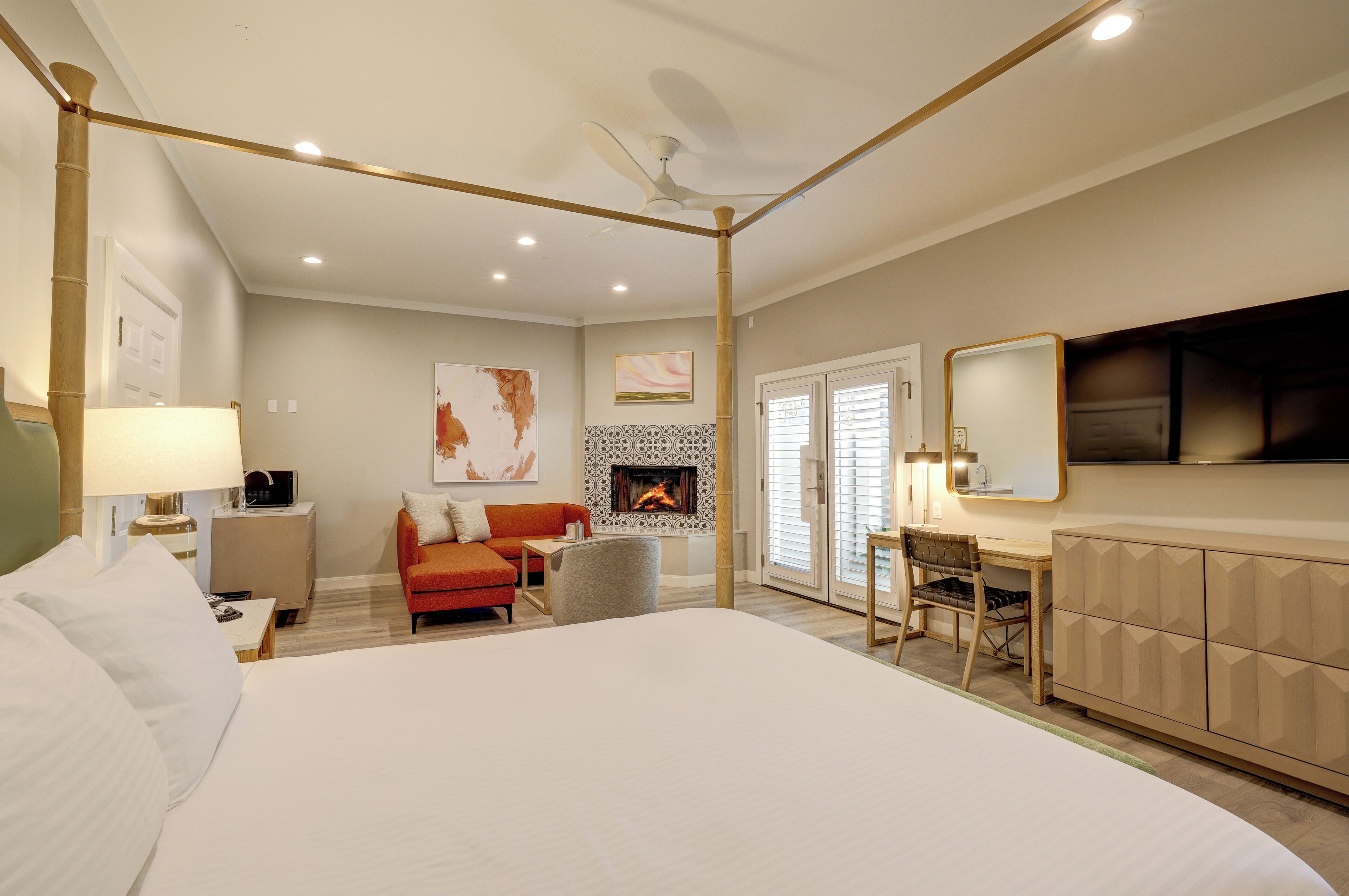 Une chambre d’hôtel avec un grand lit, un bureau, une chaise, un canapé, une cheminée et un téléviseur.