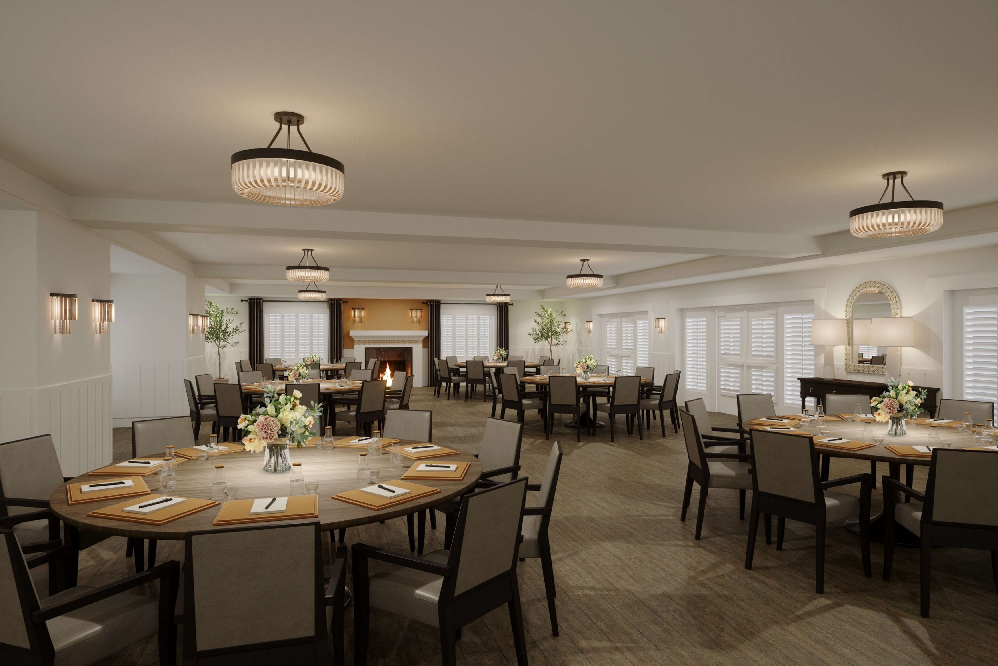 A spacious dining area with multiple round tables, chairs, and elegant chandeliers.