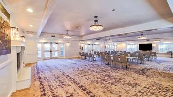 Une grande salle de conférence dotée d’un tapis à motifs, de nombreuses tables et chaises, ainsi que d’un éclairage au plafond.