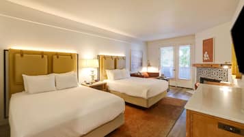A hotel room with two beds, a small kitchenette, and a bathroom with a shower and toilet.