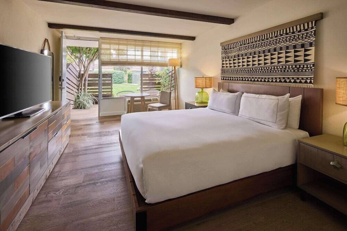Une chambre d’hôtel avec un grand lit, une télévision, un bureau avec une lampe et une vue sur l’extérieur.