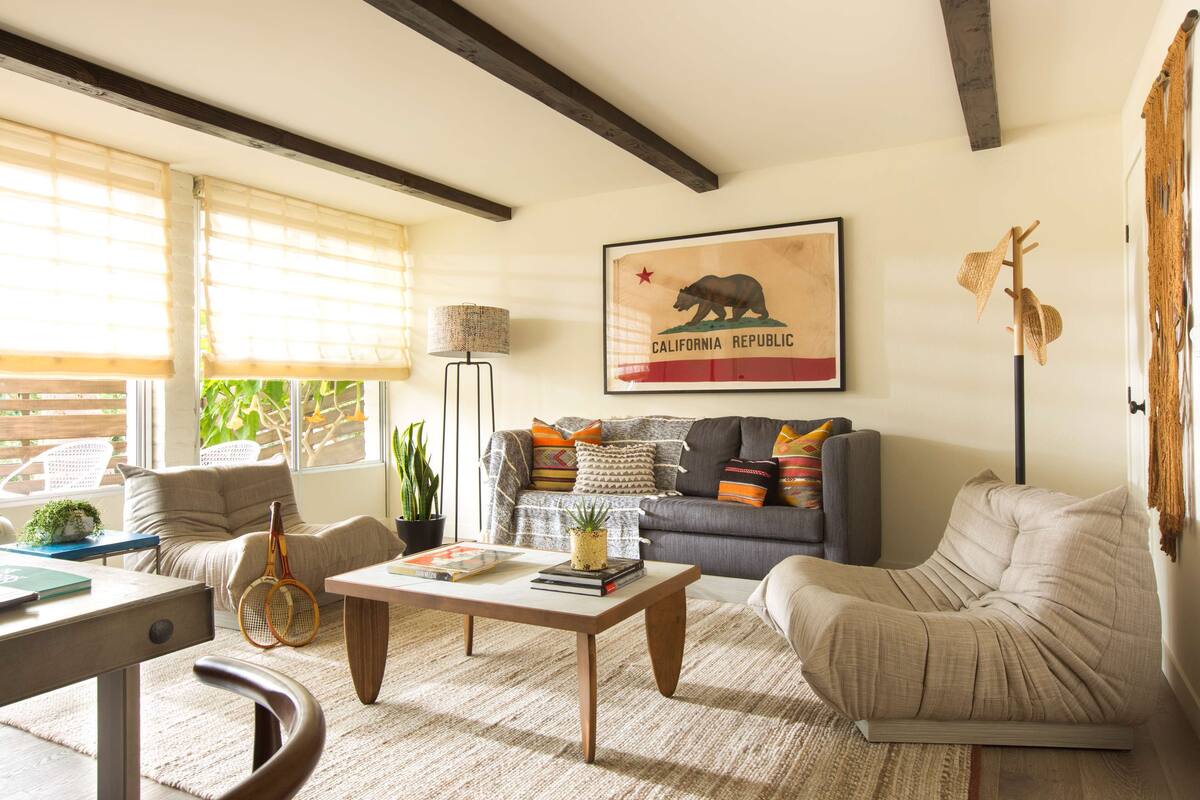 Un salon comprenant un canapé, un fauteuil, une table basse et un drapeau de l’État de Californie encadré, accroché au mur.