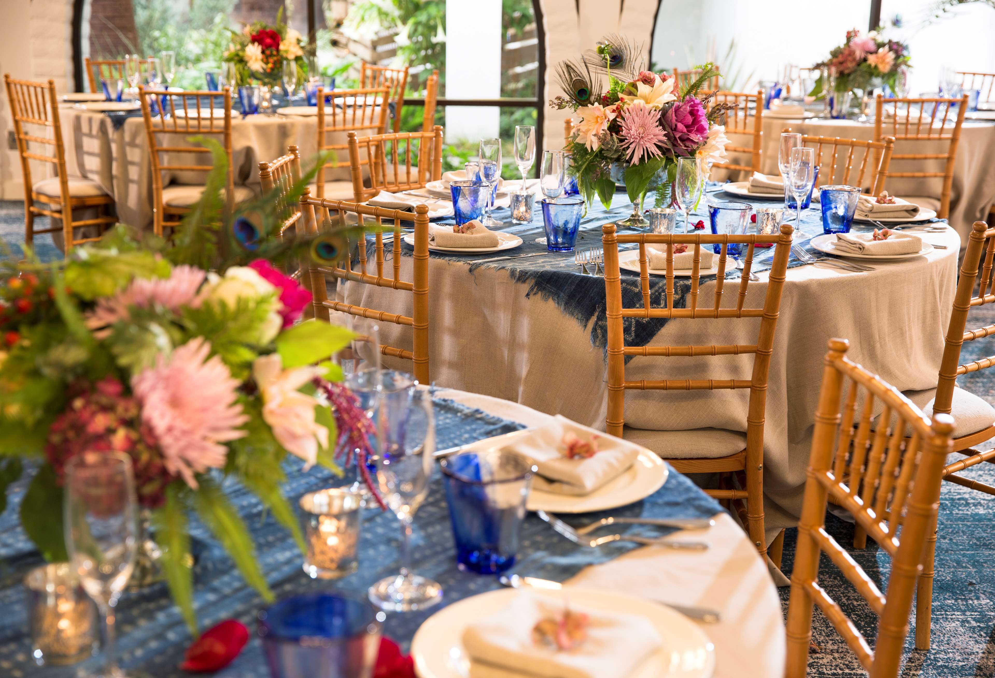 A dining area with round tables, blue tablecloths, and wooden chairs.