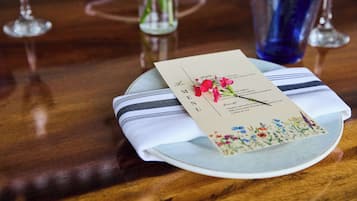 Een gedekte tafel met een menukaart op een bord, een gestreepte servet en een glas water.