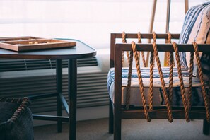 Une chaise en bois avec un dossier en corde, une table ronde avec un plateau et un coussin à rayures.