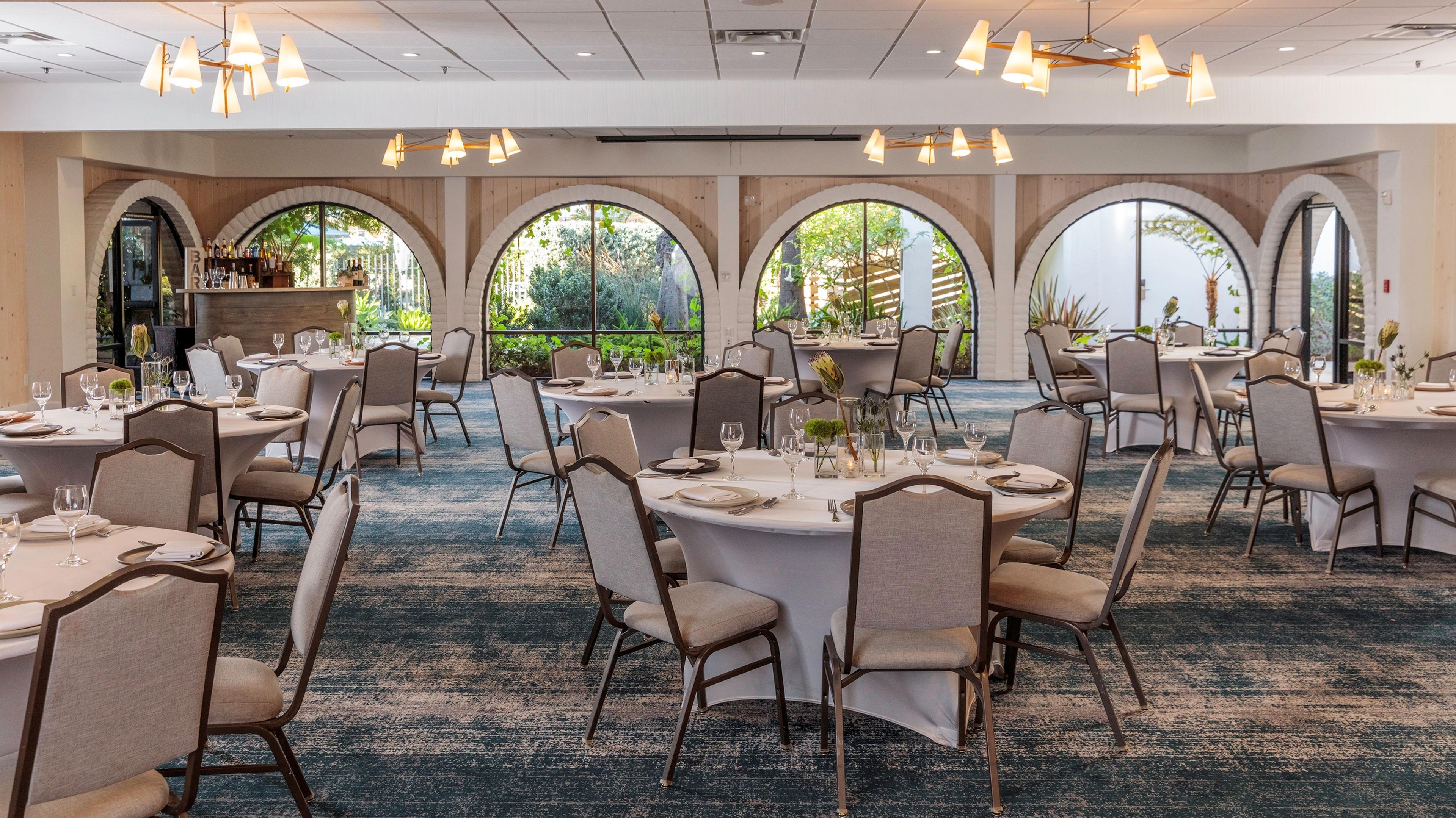 A conference room with round tables, chairs, and a carpeted floor.