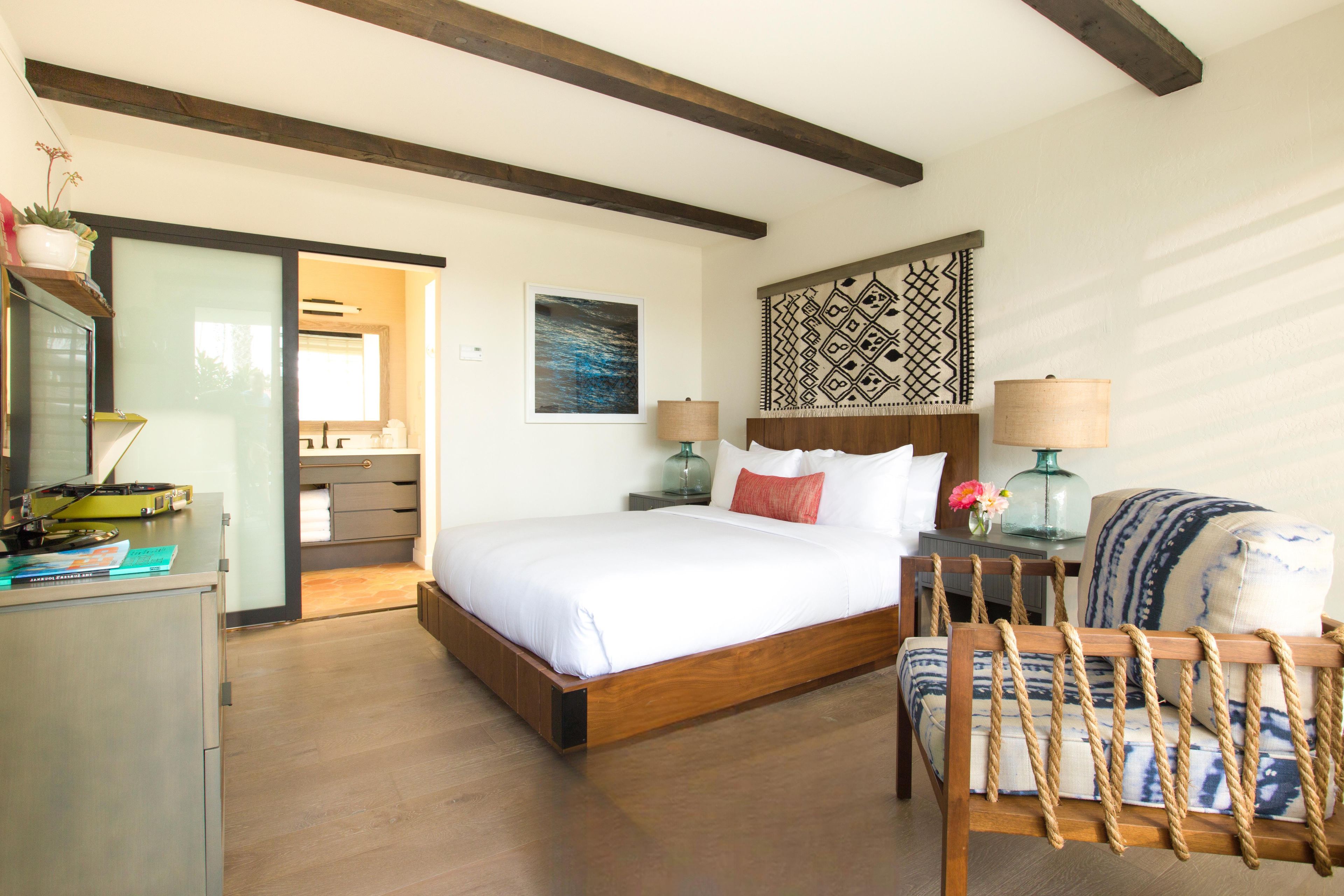 A bedroom with a wooden bed, bedside tables, a chair, and a desk with a lamp.
