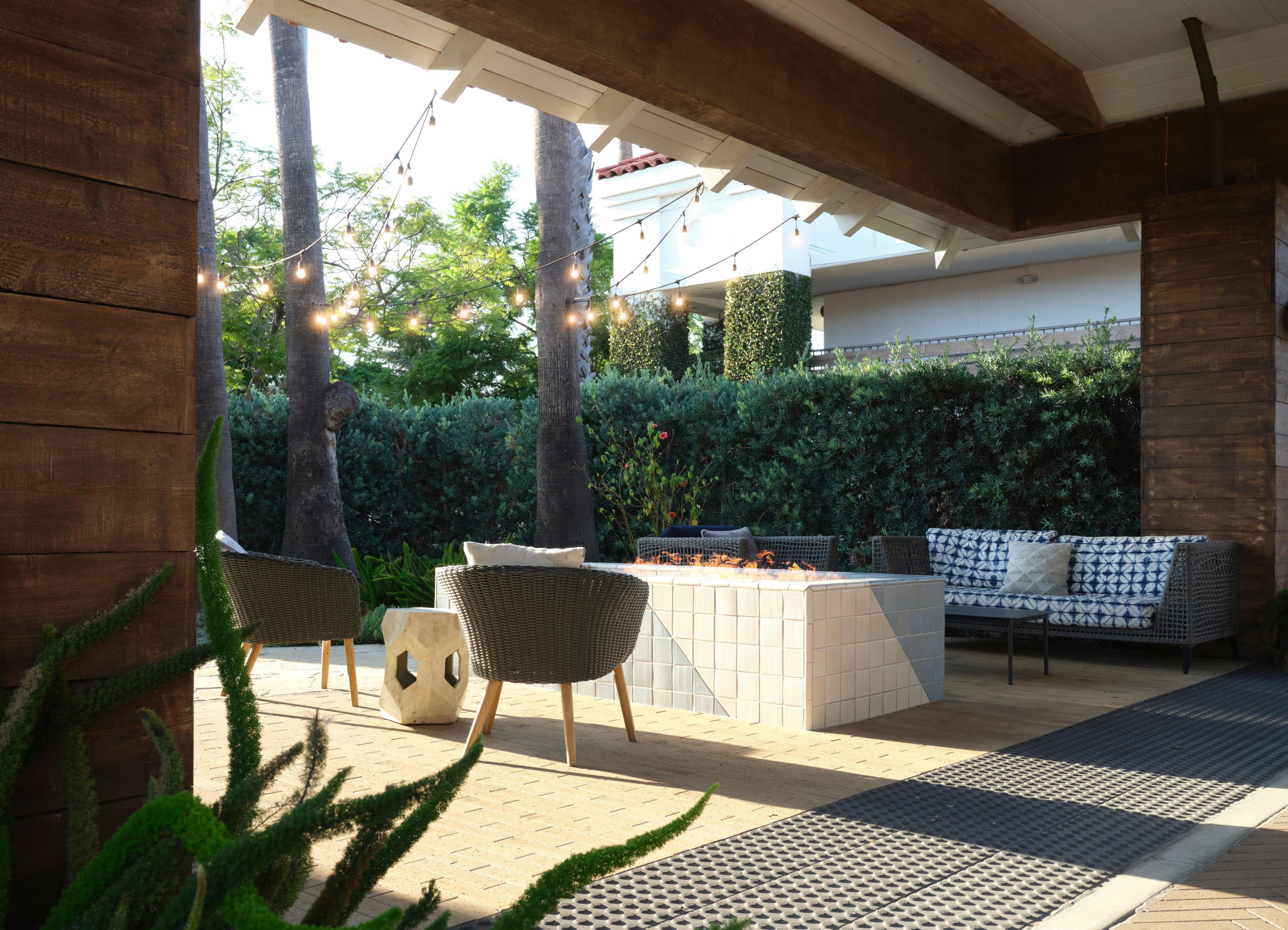 An outdoor patio with wicker furniture, a fire pit, and string lights.