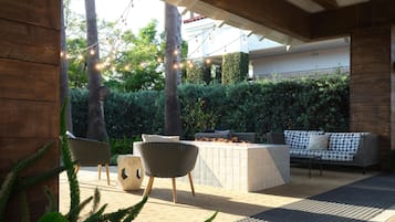 An outdoor patio with wicker furniture, a fire pit, and string lights.