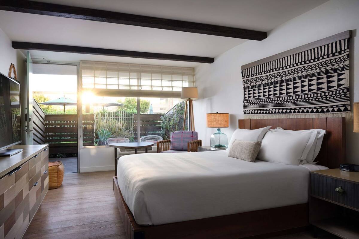 Un dormitorio con cama, mesitas de noche, televisor, escritorio y silla.