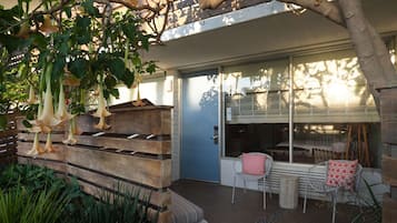 Eine Terrasse mit einer Holzbank, Stühlen und hängenden Blumen.