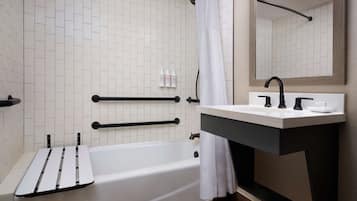 Un baño moderno con bañera, tocador con lavamanos y espejo.