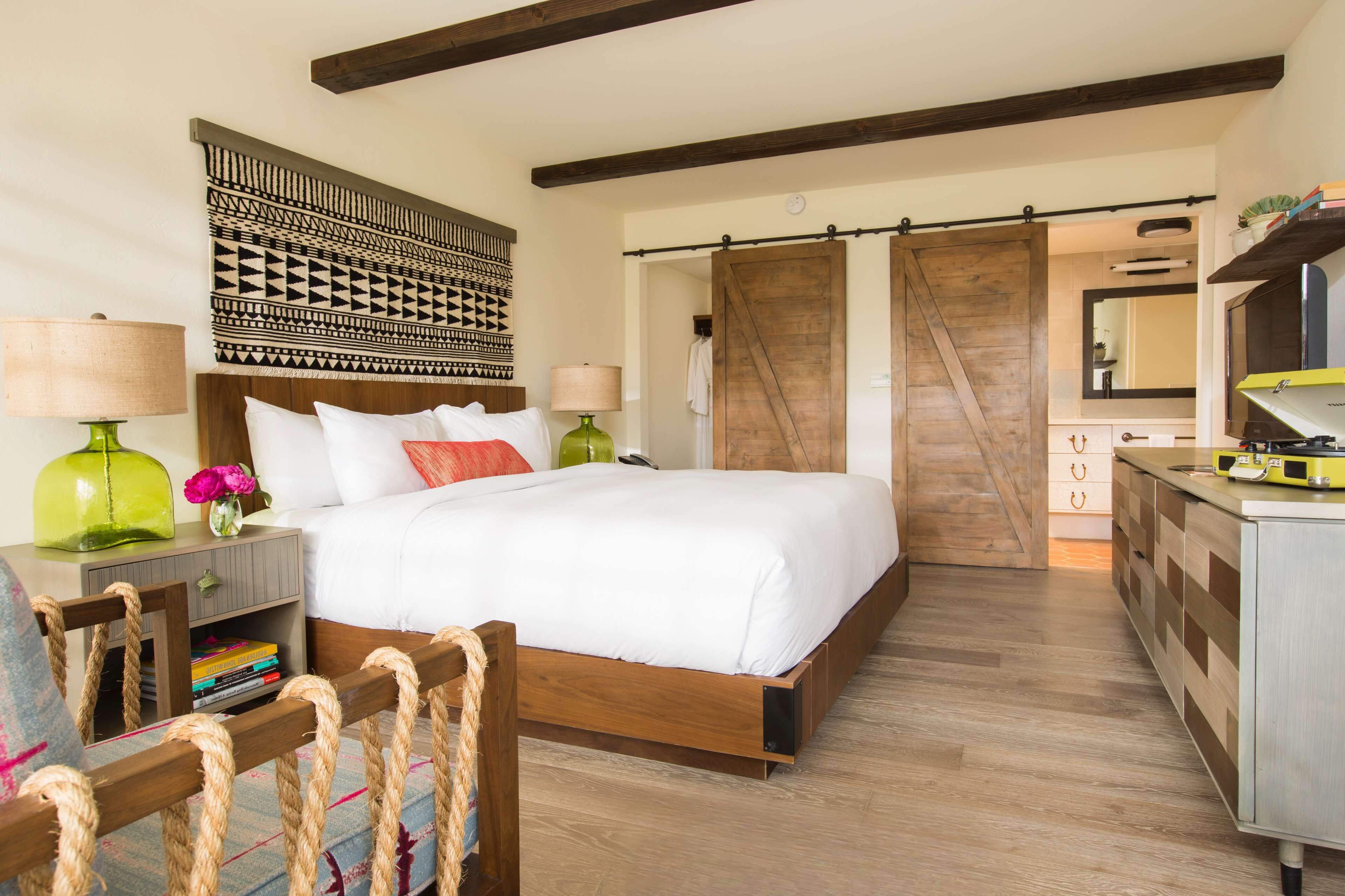 A bedroom with a wooden bed, a nightstand with a lamp, a bookshelf, and a sliding barn door closet.