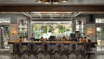 A bar area with a counter, bar stools, and a view of the outdoors through large windows.