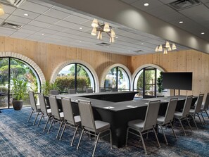 Une salle de conférence équipée d’une grande table, de chaises et d’un écran de télévision.