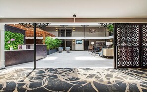 A spacious lobby with a reception desk, seating area, and a view of the upper floor. - The Burgundy Hotel, Tapestry Collection by Hilton (Little Rock)