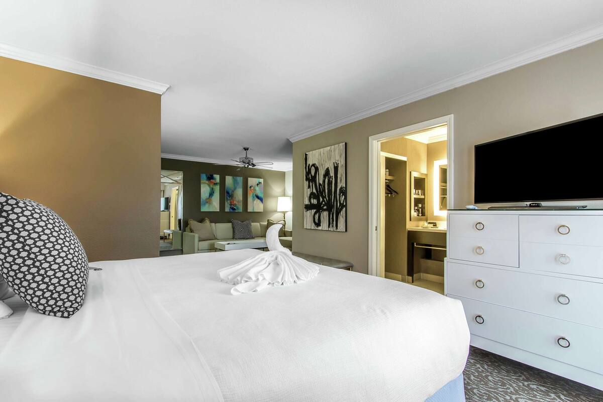 A hotel room with a large bed, a dresser, a television, and artwork on the walls.