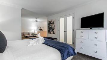 A hotel room with a bed, a dresser, a television, and a painting on the wall.