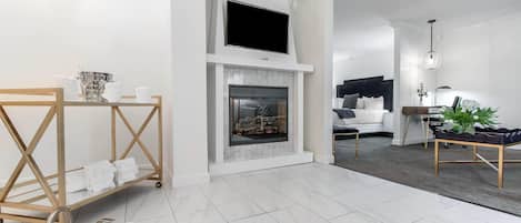 A modern living room with a fireplace, a sofa, a coffee table, and a TV mounted above the fireplace.