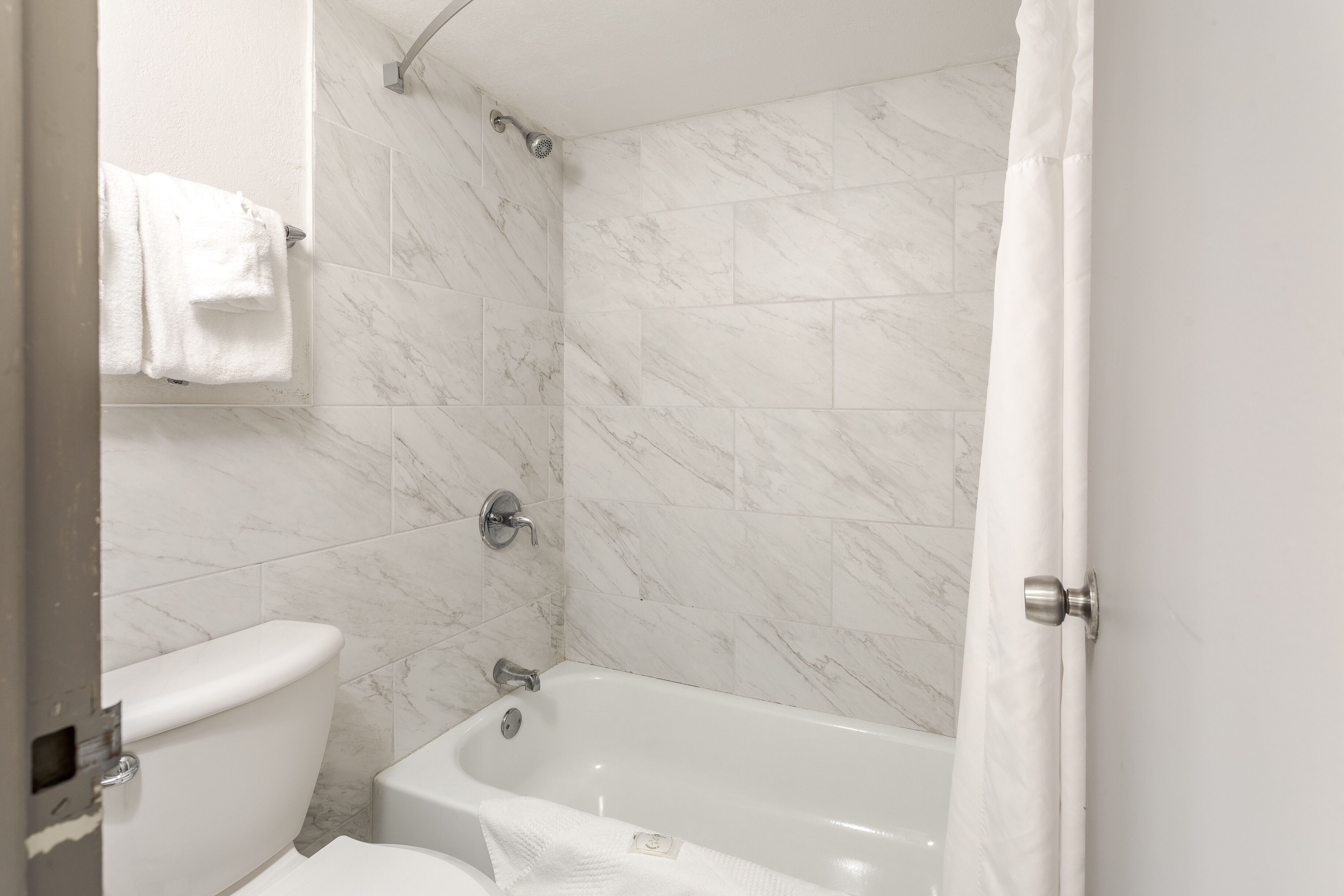 Een badkamer met toilet, bad en douchegordijn.