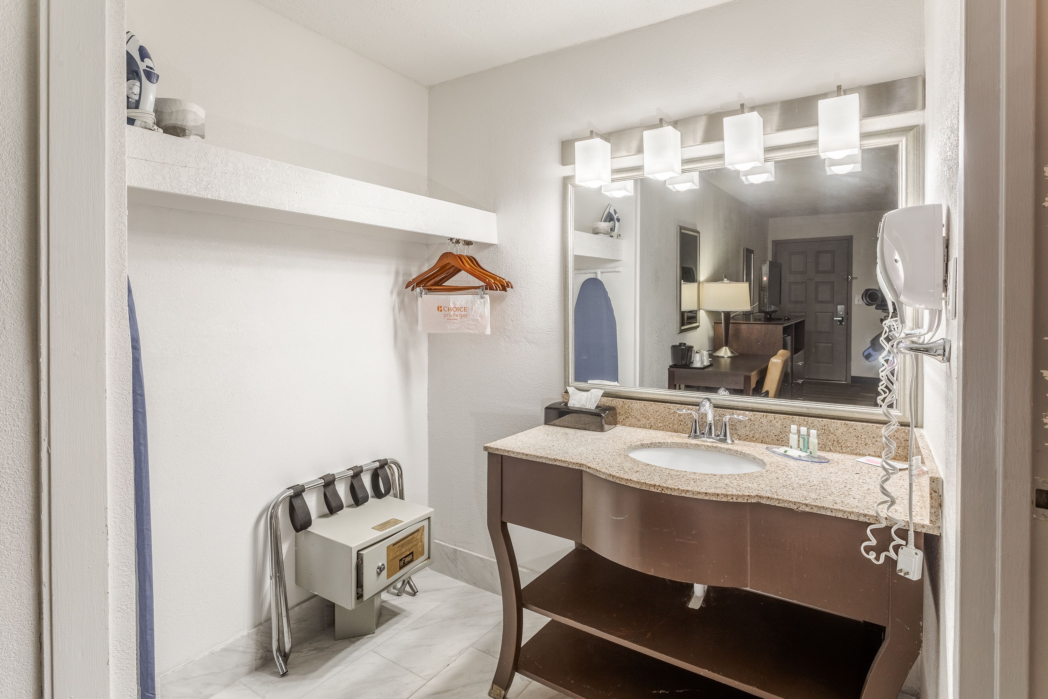 A bathroom with a sink, mirror, towel rack, and a vanity with a towel hanging.