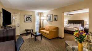 A hotel room with a bed, a sofa, a TV, a desk, and a coffee table. - Quality Inn University (Lansing)