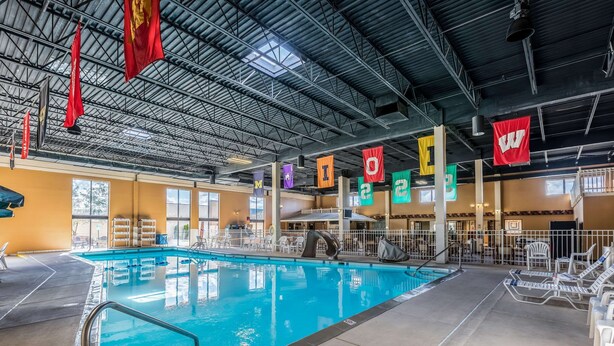 An indoor swimming pool with clear water, surrounded by lounge chairs and a poolside area. - Quality Inn University (Lansing)