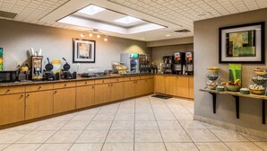 A clean, well-lit kitchen area with a long counter, equipped with various appliances and food displays. - Quality Inn University (Lansing)
