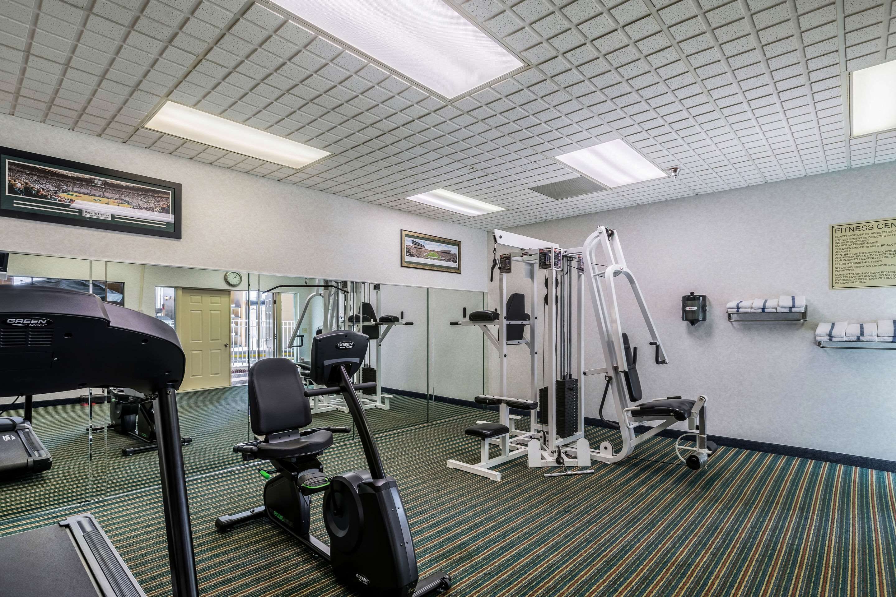 A gym with exercise equipment, mirrors, and a fitness center sign.