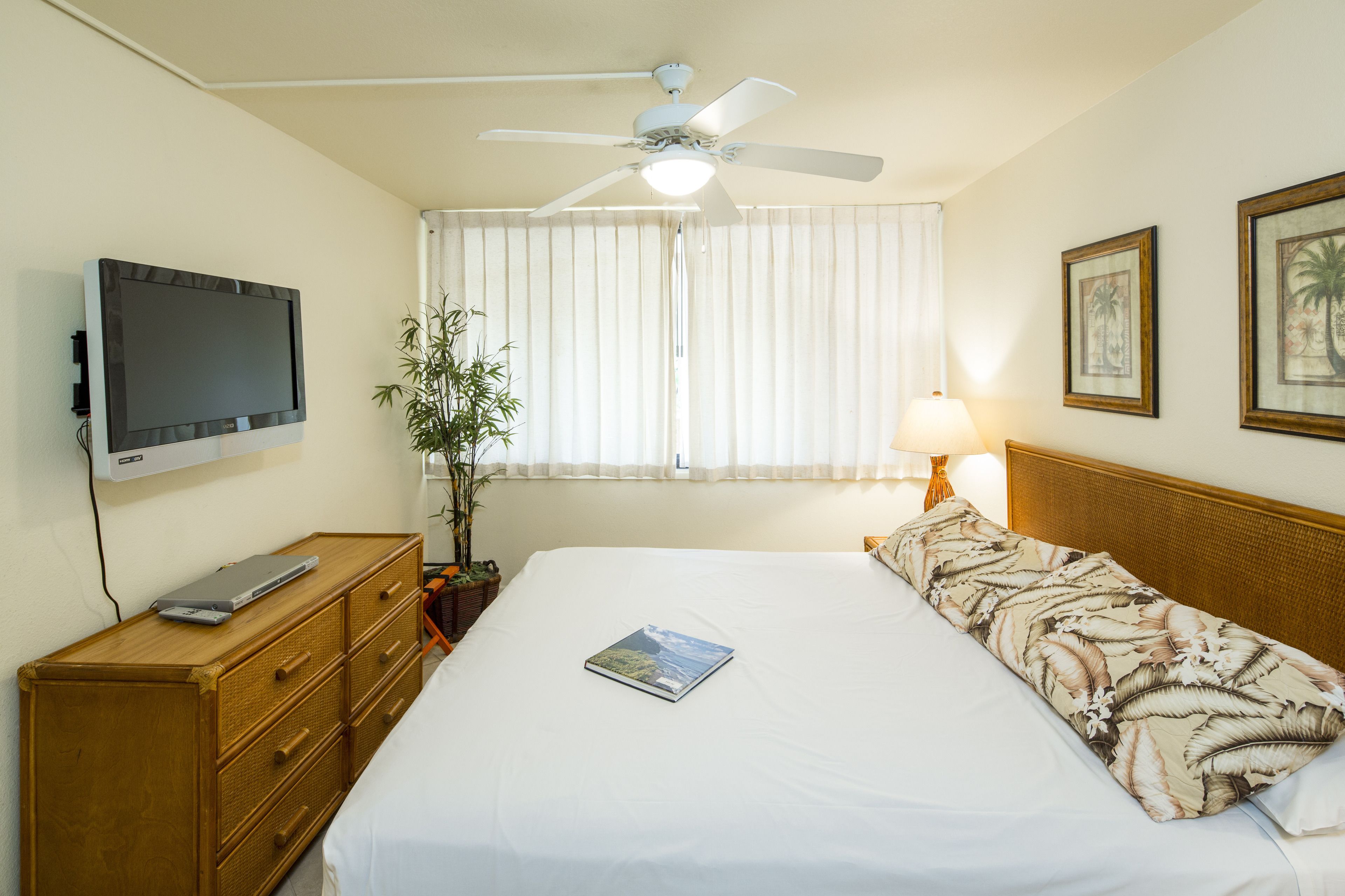 A hotel room with a bed, a television, a desk, a lamp, and a window with curtains.