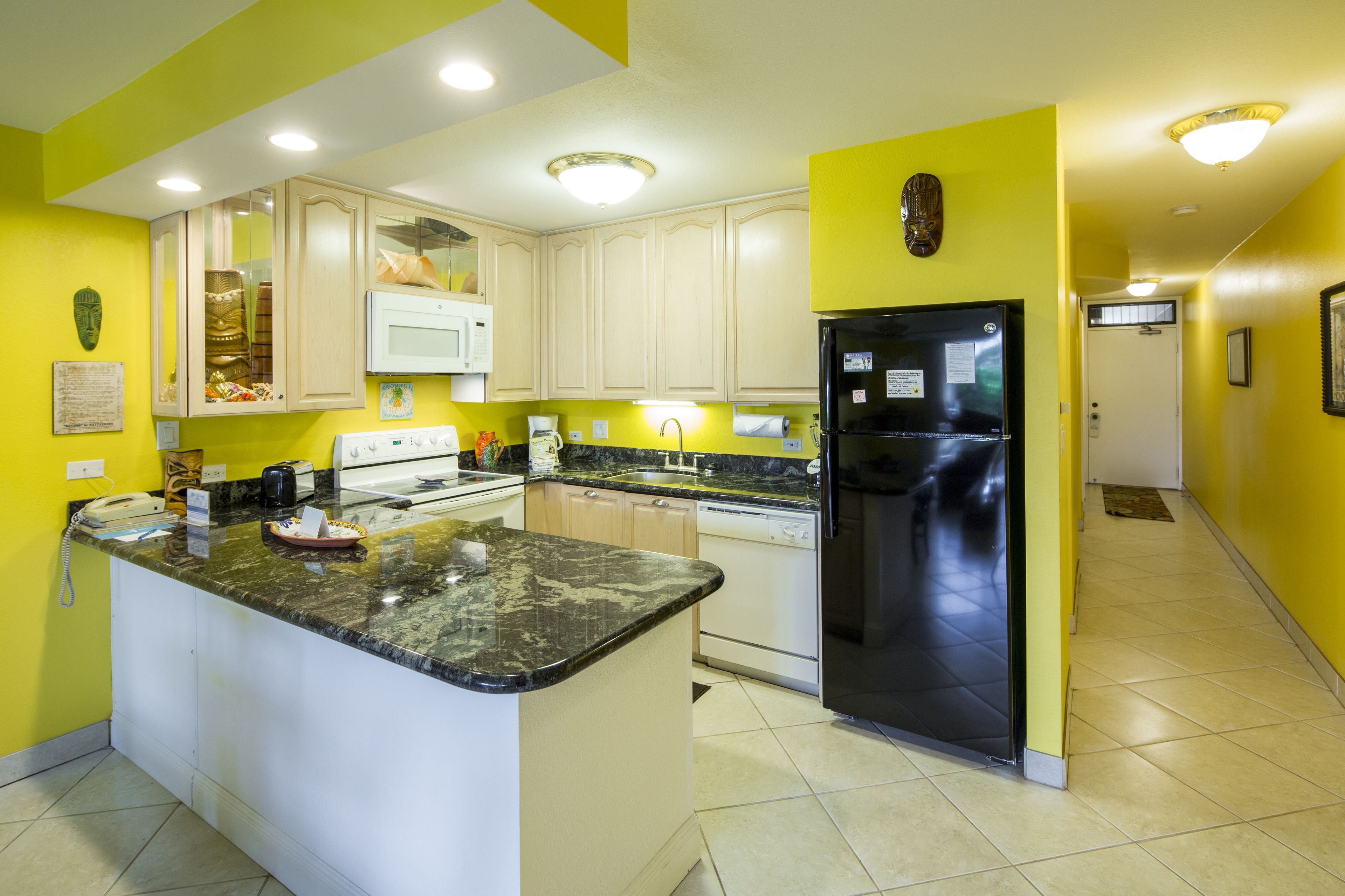 A kitchen with a central island, white cabinets, a black refrigerator, and a microwave.