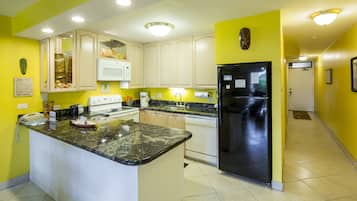 A kitchen with a central island, white cabinets, a black refrigerator, and a microwave.