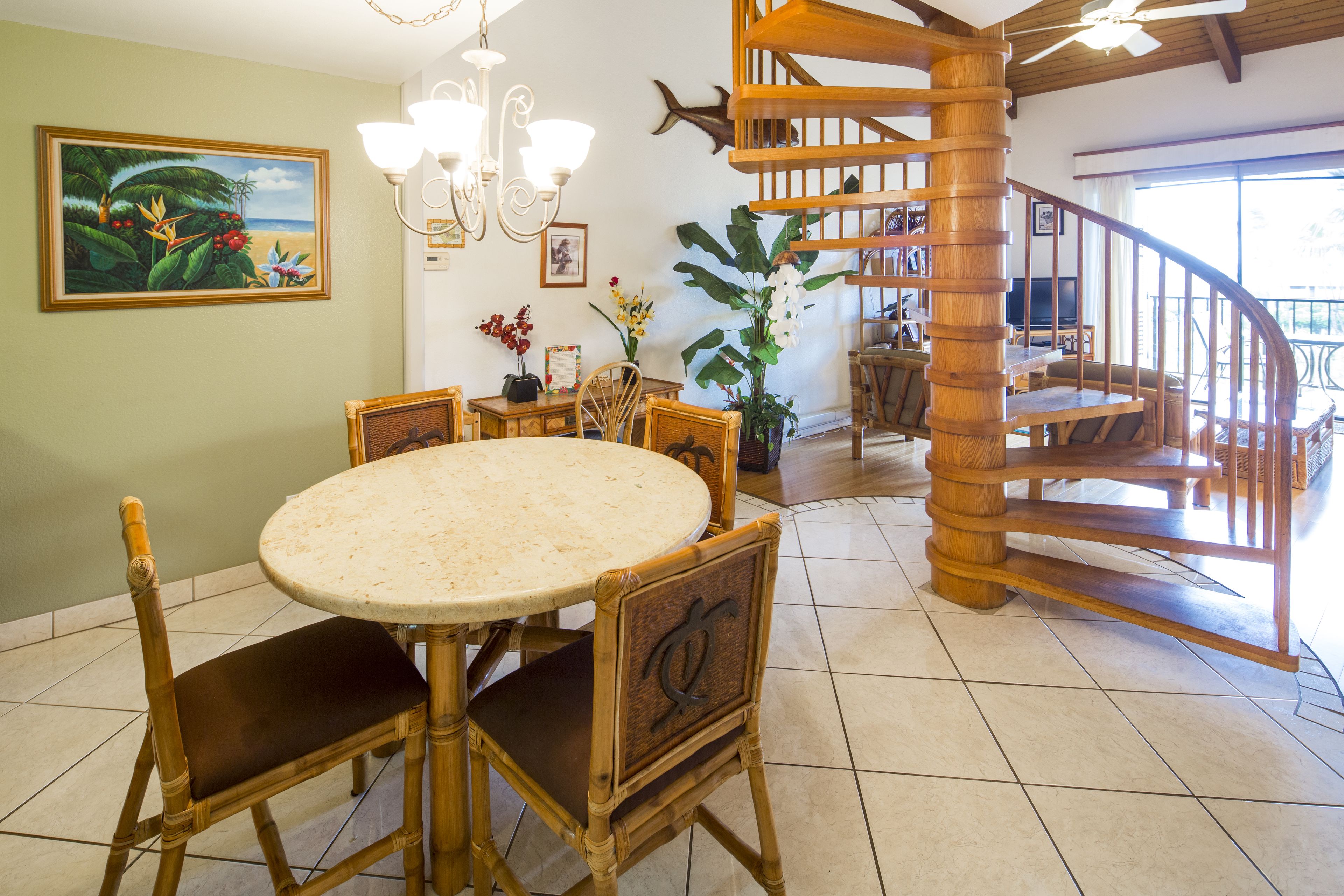 A dining area with a round table and chairs, a staircase, and a large potted plant.