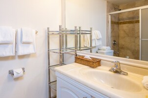 Baño con lavamanos, espejo, toallero y zona de ducha.