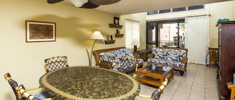 A dining area with a round table, chairs, a ceiling fan, and a window with blinds.