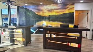 A reception desk with a mural of a sunset over a lake, wooden paddle boats, and a ceiling fan. - Comfort Inn & Suites Denver West - Golden (Golden)