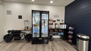 A hotel lobby with a refrigerator stocked with beverages, a coffee machine, a trash can, and a shuttle service sign. - Comfort Inn & Suites Denver West - Golden (Golden)