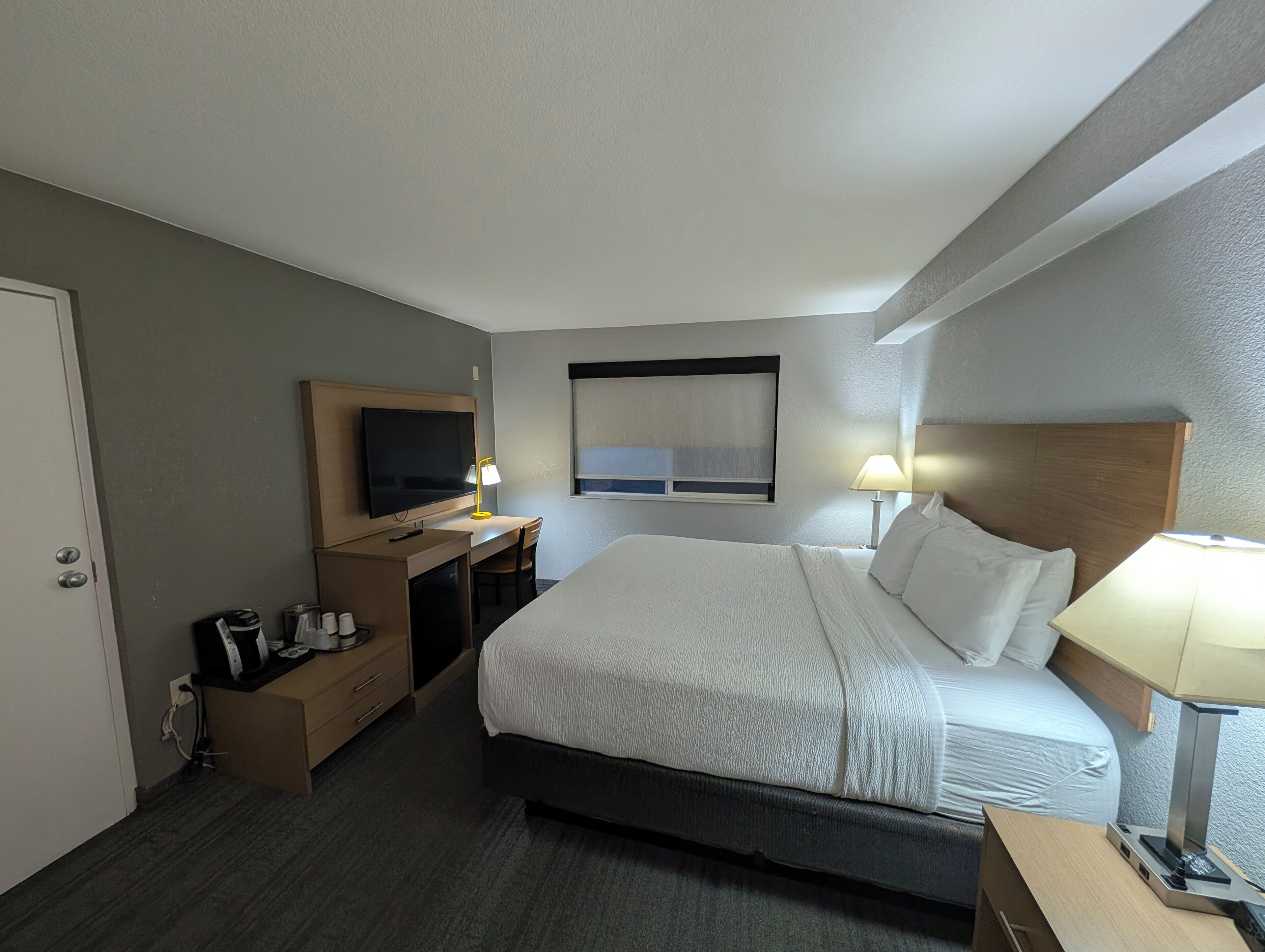Une chambre d’hôtel avec un lit, un bureau, une télévision et une fenêtre.