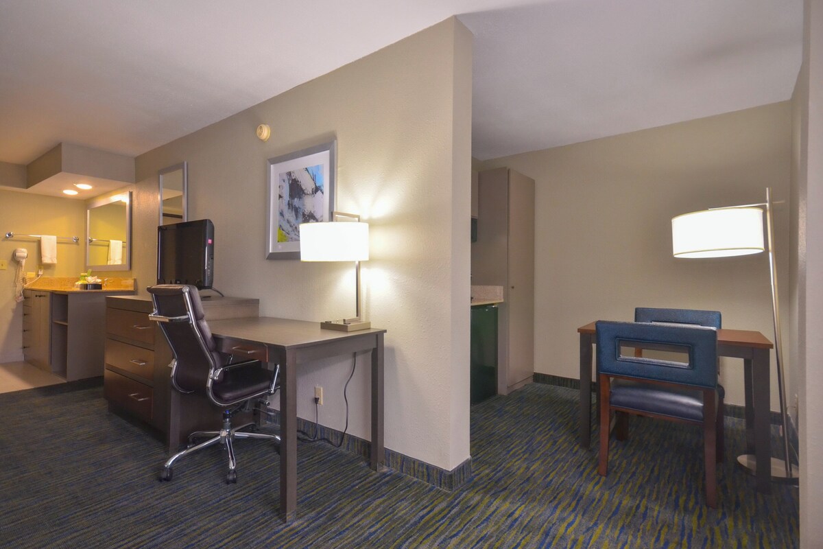 A hotel room with a desk, chair, and a bed.