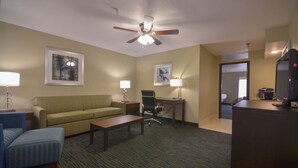 A hotel room with a sofa, a desk, a chair, a coffee maker, and a television. - Holiday Inn Express Fayetteville- Univ of AR Area by IHG (Fayetteville)