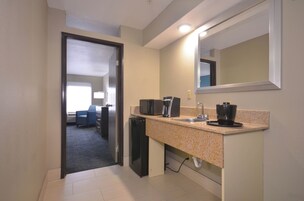 A hotel bathroom with a sink, mirror, and a coffee maker.