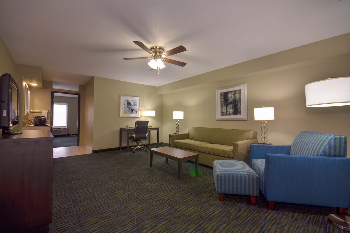 A hotel room with a ceiling fan, a sofa, a small table, and a TV.