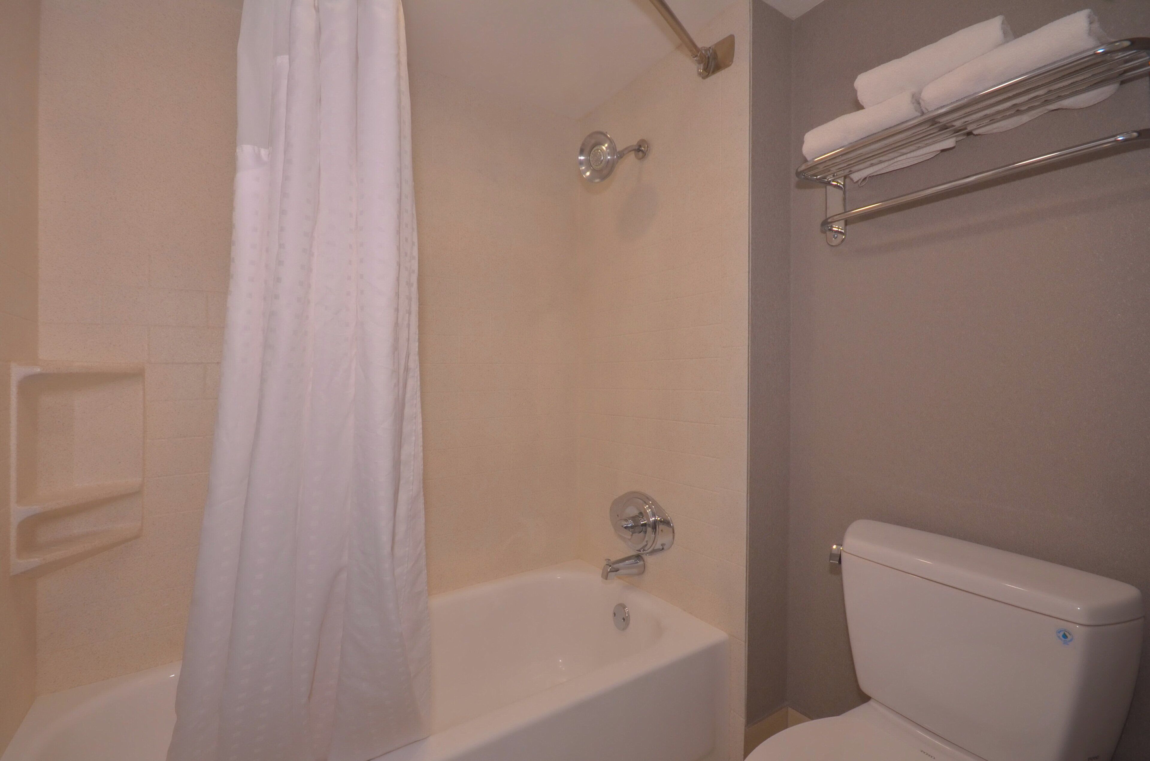 Un baño con bañera, inodoro y barra para toallas.