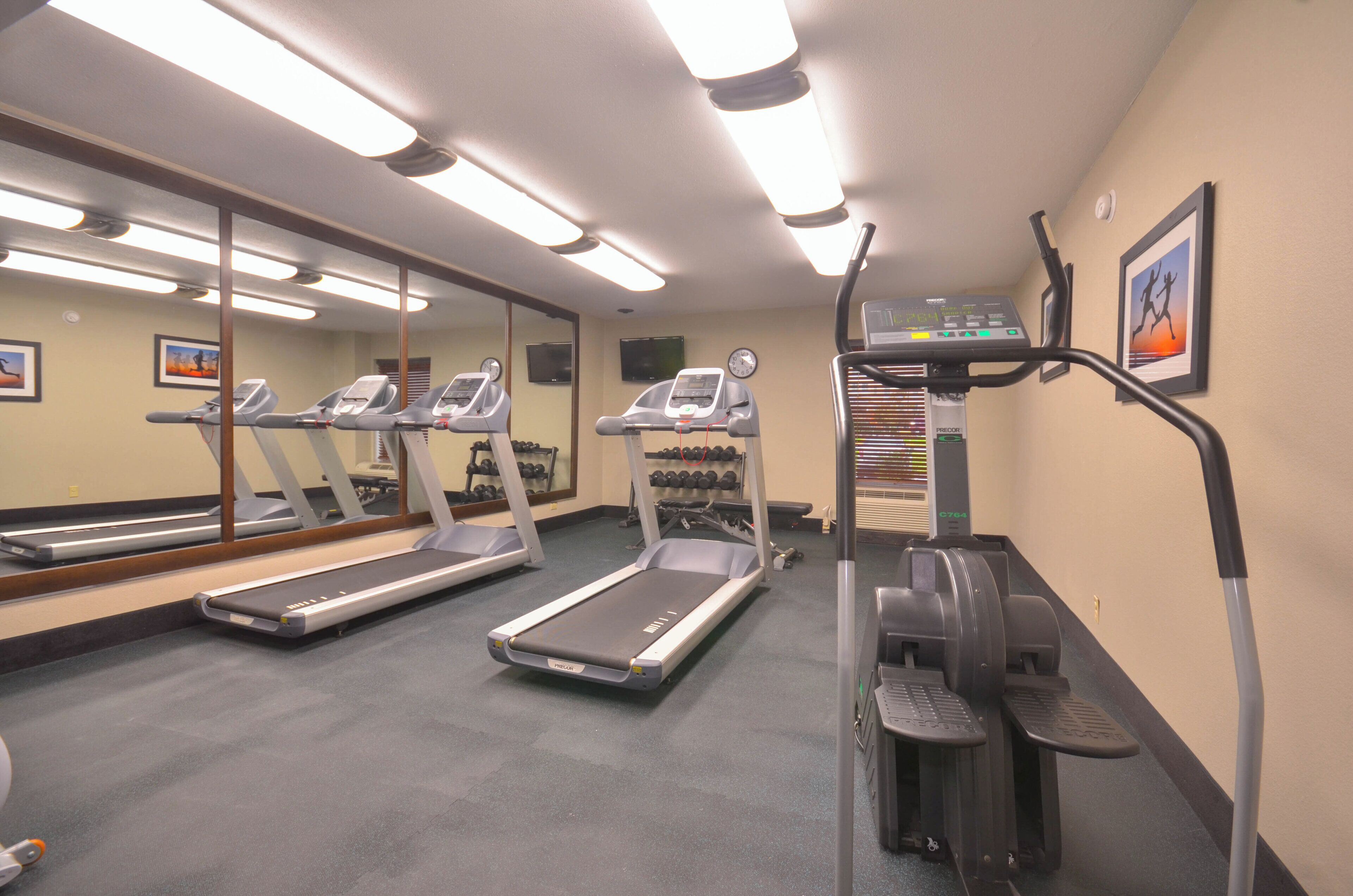A gym with treadmills, a stair climber, and a wall-mounted TV.