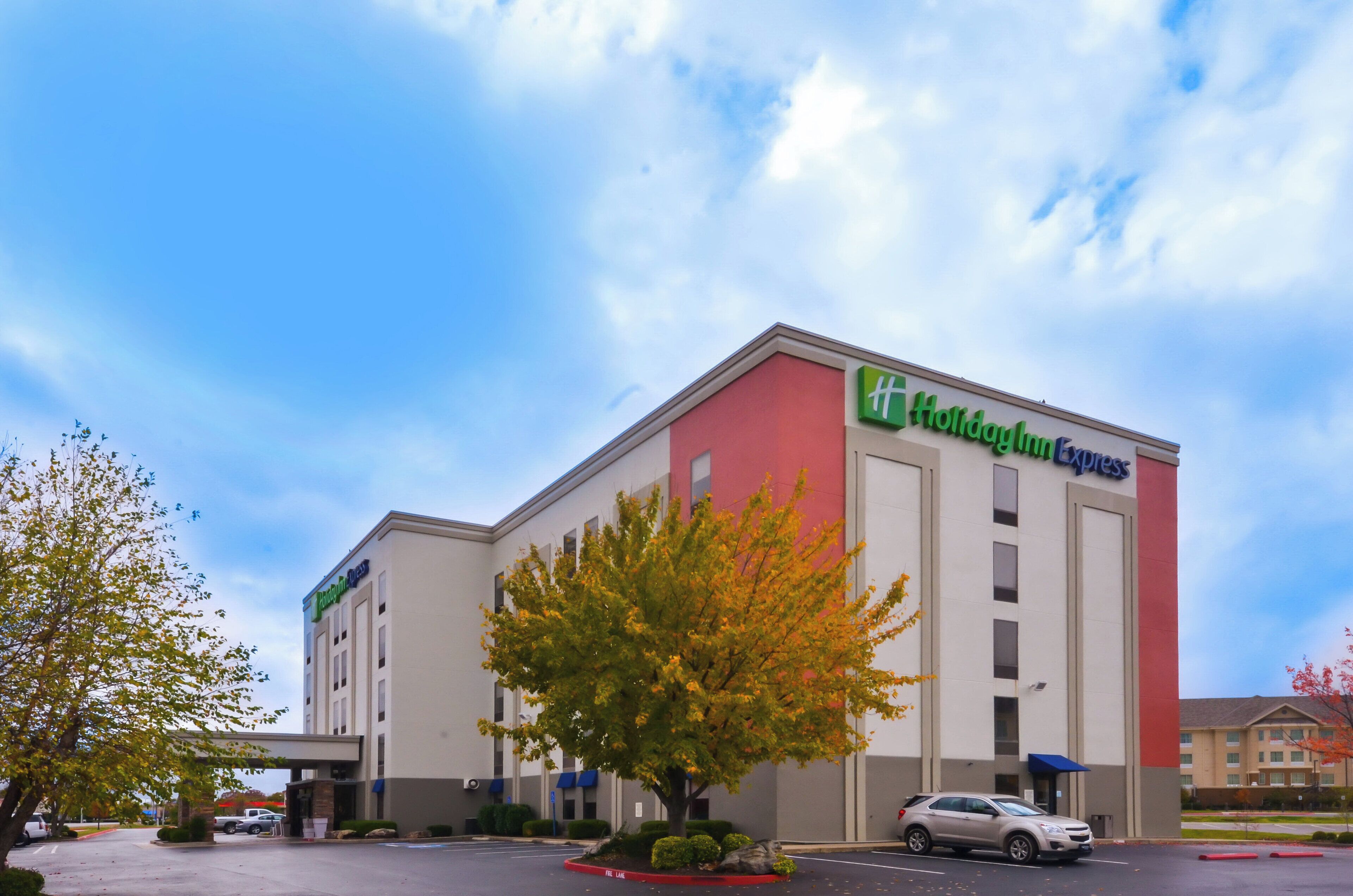 A Holiday Inn Express hotel with a parking lot and a tree in front.