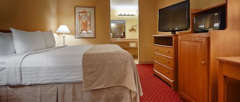 A hotel room with a bed, a dresser, a television, and a microwave.