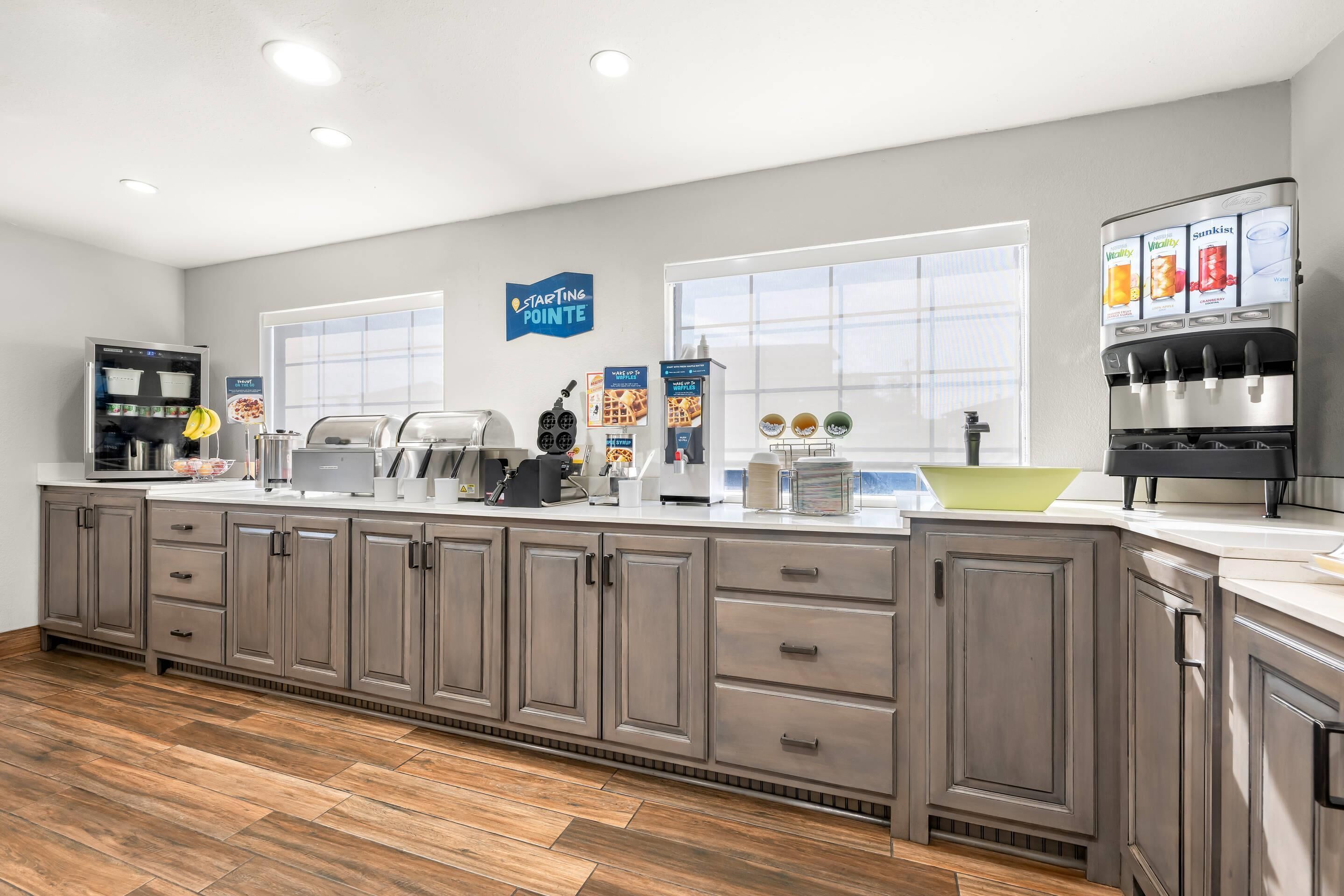 A modern kitchen with a long counter, built-in appliances, and a starting pointe sign on the wall.